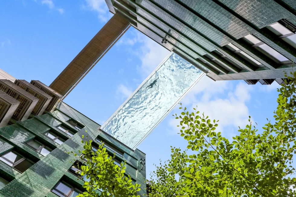 A swimmer seen from below through the transparent base of the Sky Pool