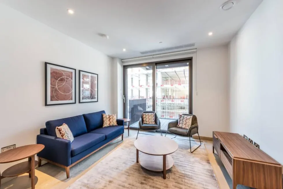 Reception room with a blue sofa, armchairs and sliding glazed doors to the balcony