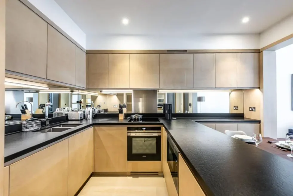 Kitchen with mirrored splashback, integrated oven and hob, and the dining table beyond