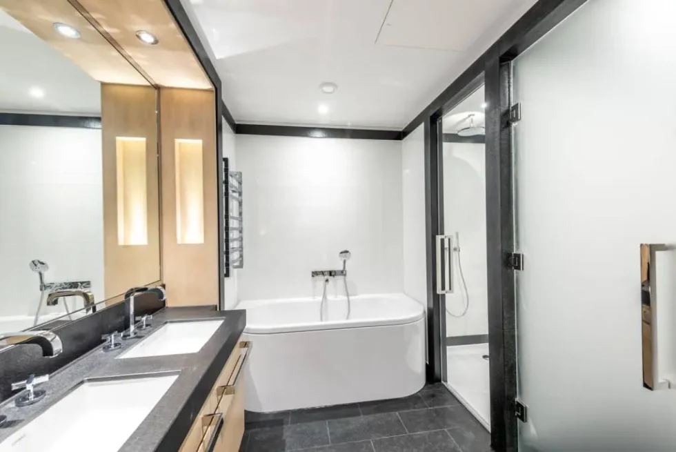 En-suite bathroom with twin basins, a corner bath and a separate glazed shower