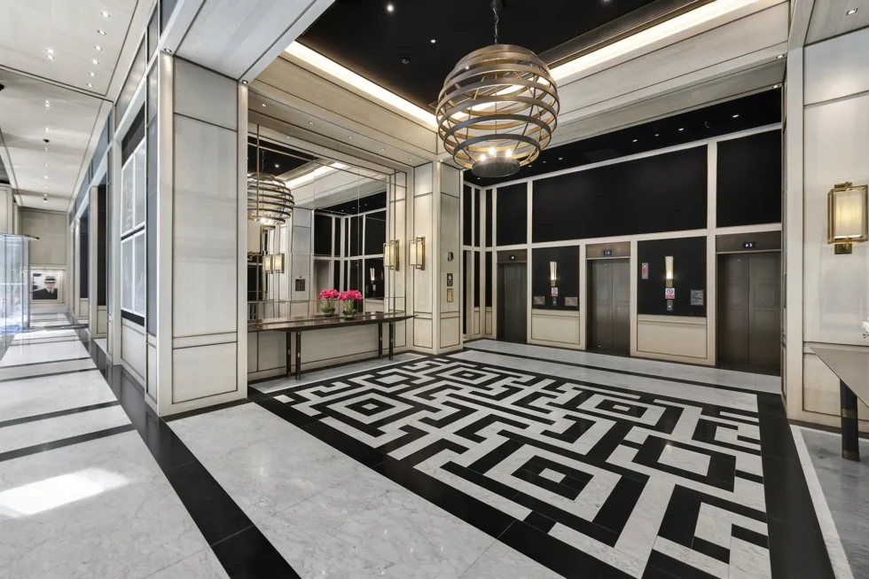 The Grand Foyer, with a patterned marble floor, brass chandelier and lift bank