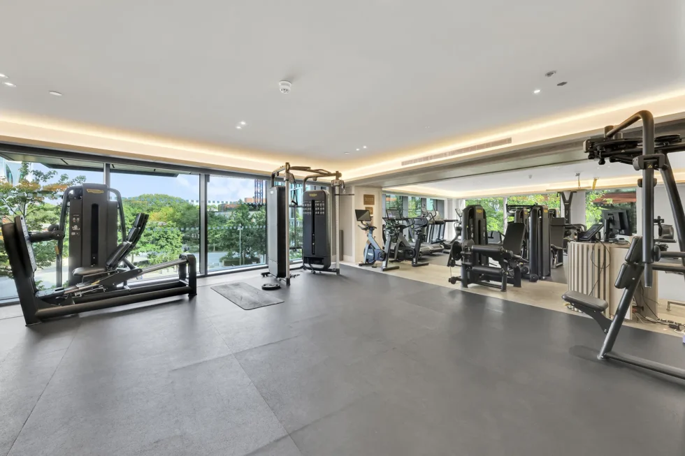 Residents' gym with resistance and cardio machines and full-height windows onto greenery