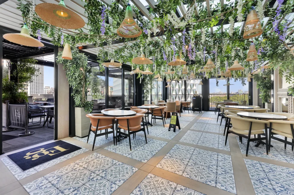 Rooftop bar with patterned tiling, rattan pendant lights and trailing foliage overhead