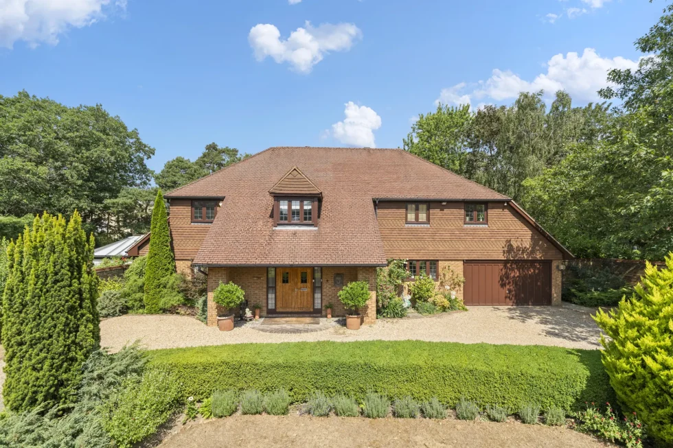 Front elevation of Silver Birch, a seven-bedroom house in Queensgate, Cobham, with gravel driveway and box hedging