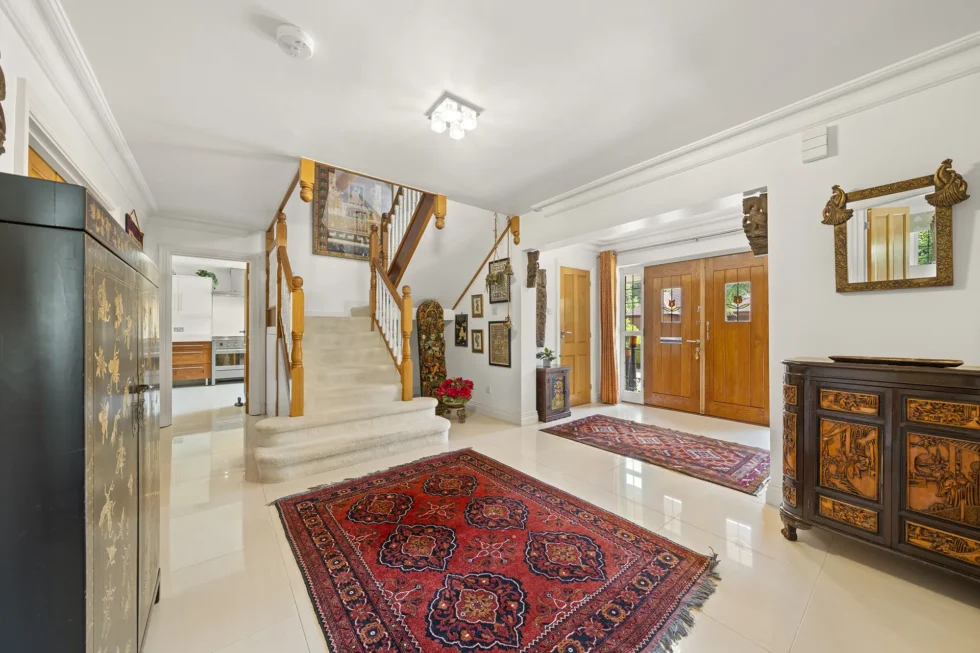 Entrance hall with tiled floor and carpeted staircase, looking towards the glazed oak front doors