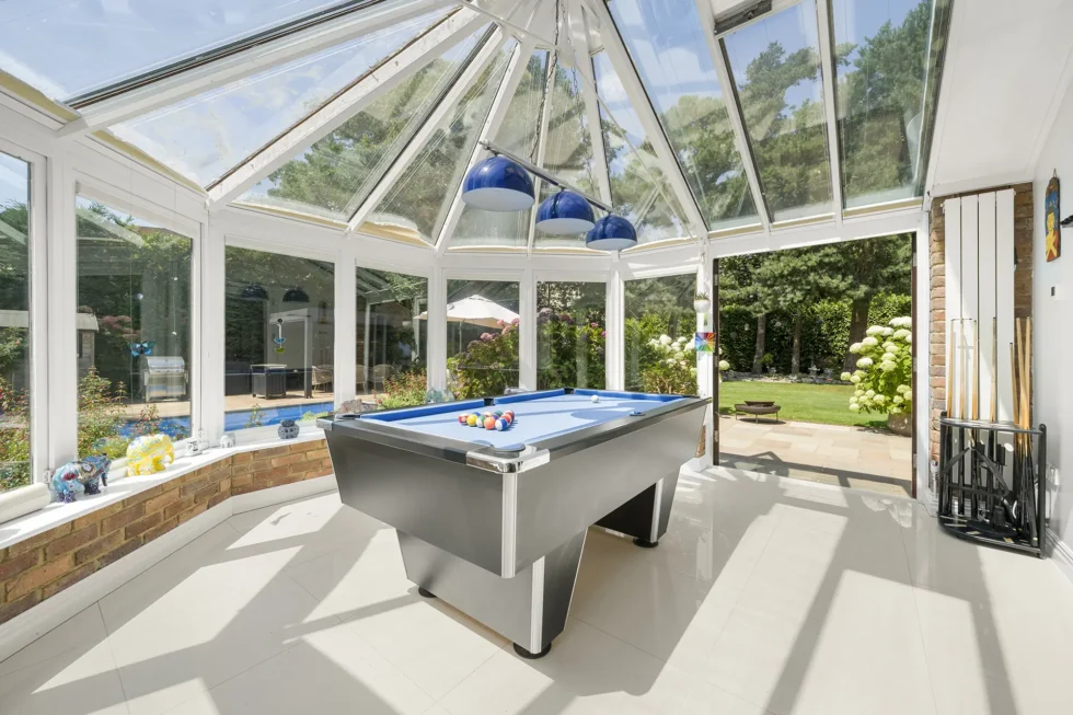Glazed conservatory with pool table, opening onto the terrace and swimming pool