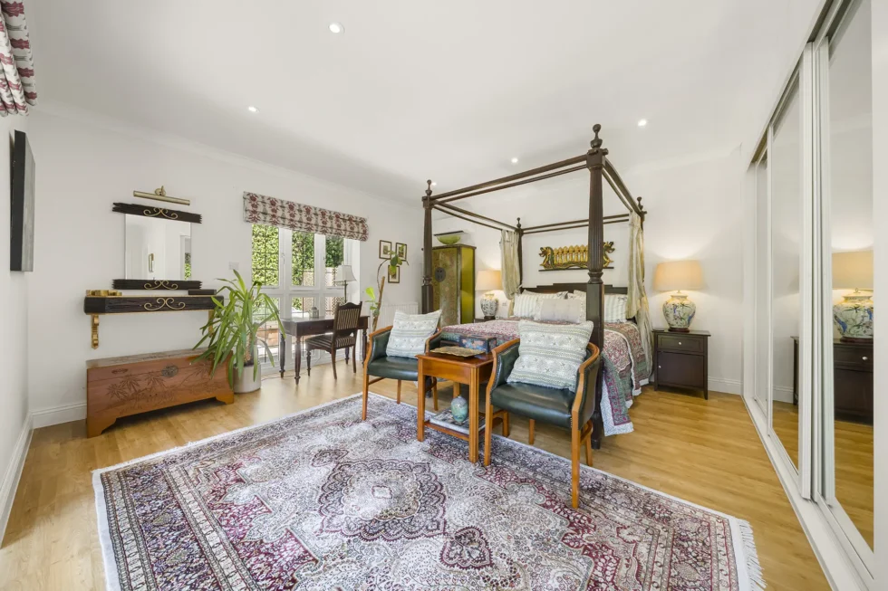 Bedroom with four-poster bed, oak floor and mirrored fitted wardrobes