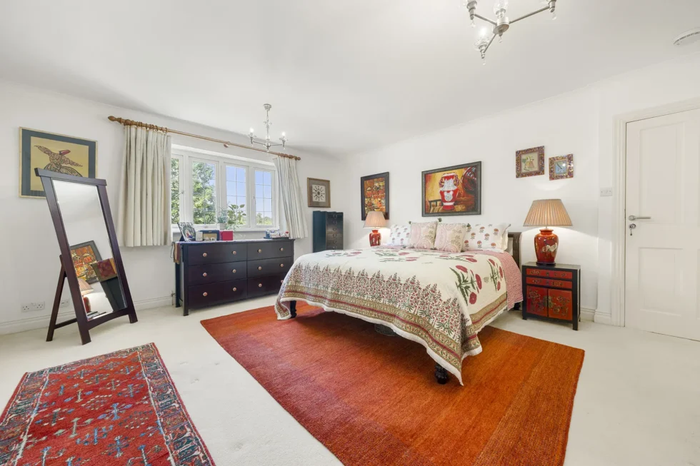 Principal bedroom with double bed, cheval mirror and window overlooking the garden