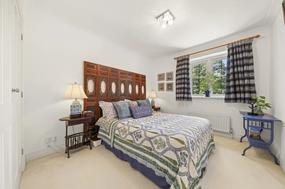 Double bedroom with carved wooden screen headboard and fitted wardrobe