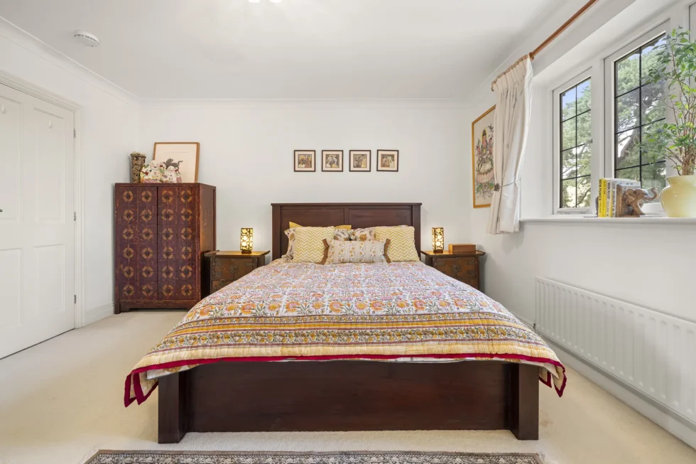 Double bedroom with dark wood bed frame, antique chest and deep windowsill