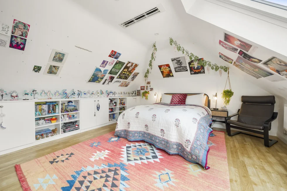 Converted loft bedroom with vaulted ceiling, skylights, wood floor and fitted low-level storage