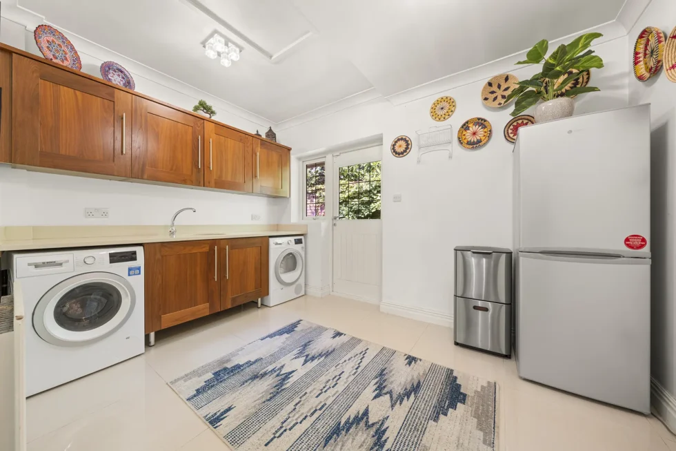 Utility room with walnut units, sink, washing machine, tumble dryer and door to the garden
