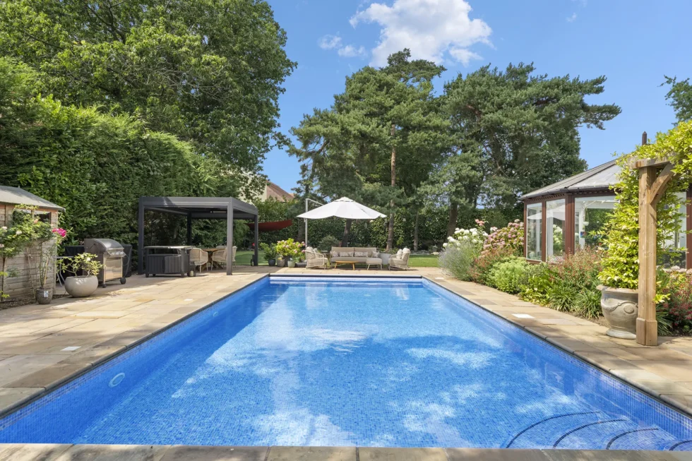 Outdoor swimming pool with sandstone surround, covered dining pergola and barbecue area