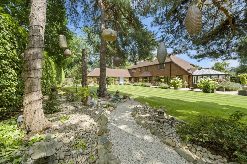 View across the lawn towards the house, past a gravel garden with stone lanterns and hanging lights