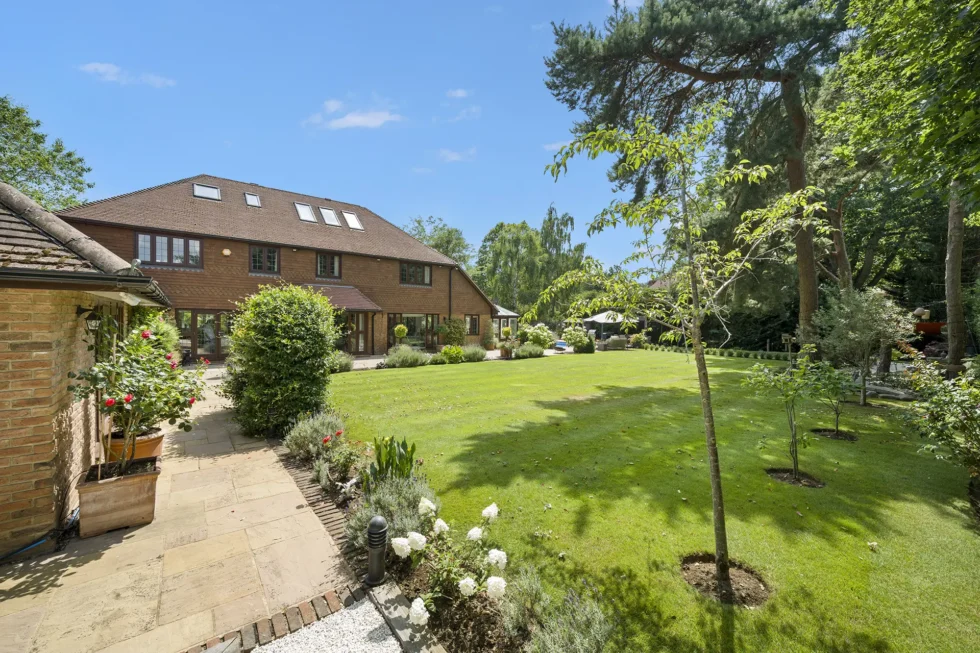 Rear elevation and lawn seen from the side of the garden, with rose planting and young specimen trees